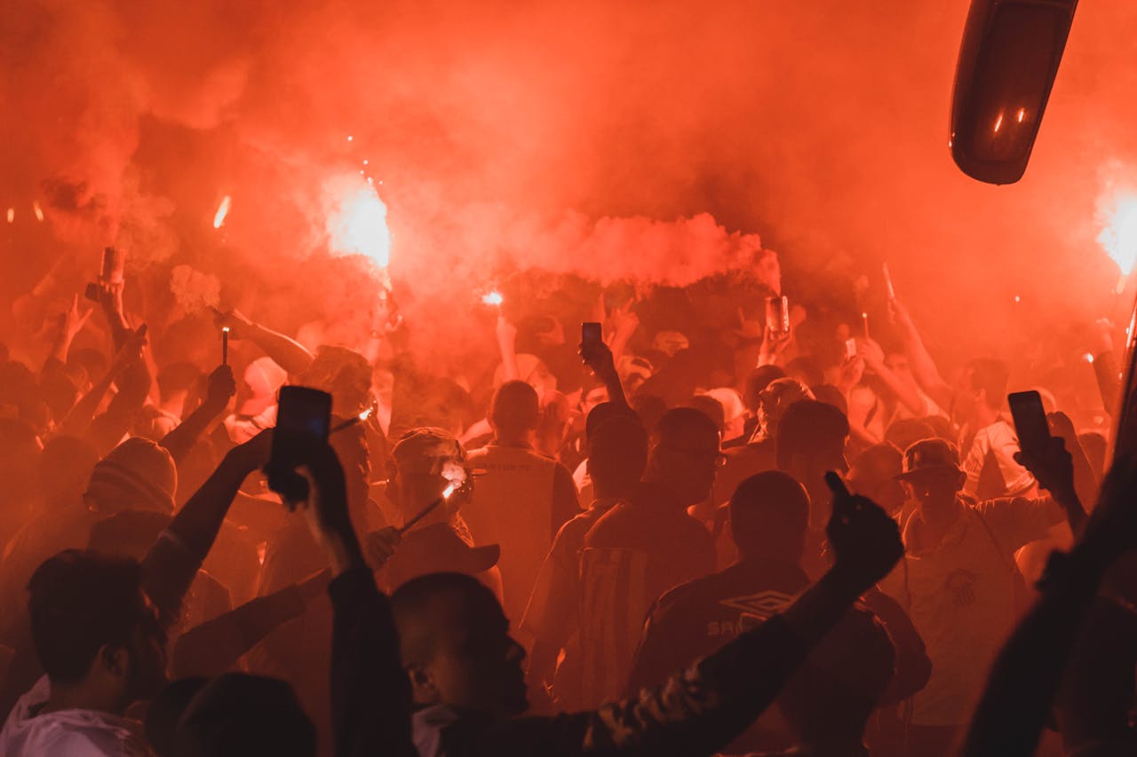 A dynamic crowd enjoying a nighttime party with vibrant flares and smoke, creating a lively atmosphere.